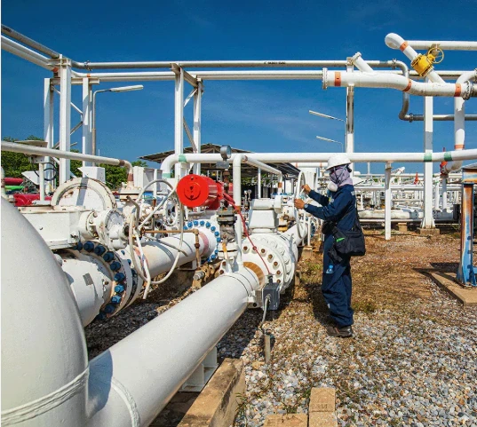 Técnico inspeccionando válvulas y tuberías en una instalación de petróleo y gas